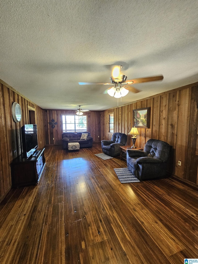 unfurnished living room with ceiling fan, wood walls, and dark hardwood / wood-style flooring