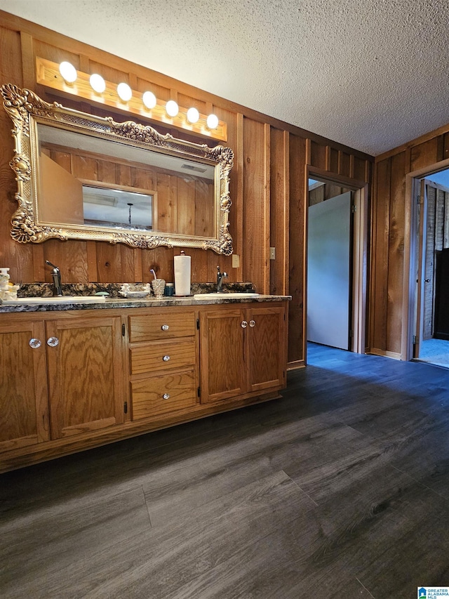 kitchen with sink, a textured ceiling, and wood walls