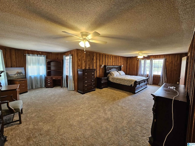 carpeted bedroom featuring a textured ceiling, ceiling fan, and wood walls