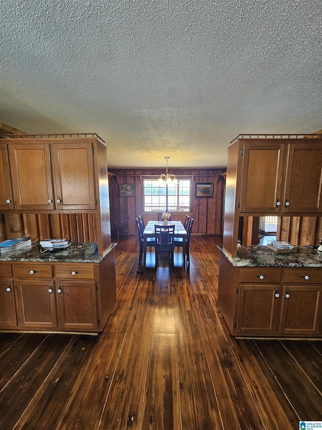 kitchen featuring pendant lighting, wood walls, dark hardwood / wood-style flooring, and an inviting chandelier