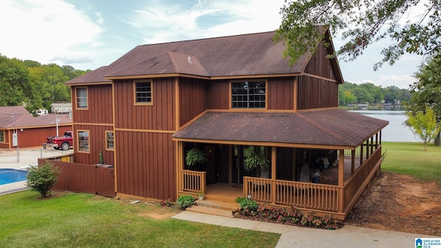 rear view of property with a yard, a water view, and a porch