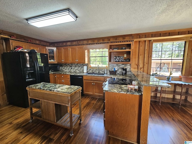 kitchen featuring a textured ceiling, dark wood-type flooring, sink, black appliances, and a center island