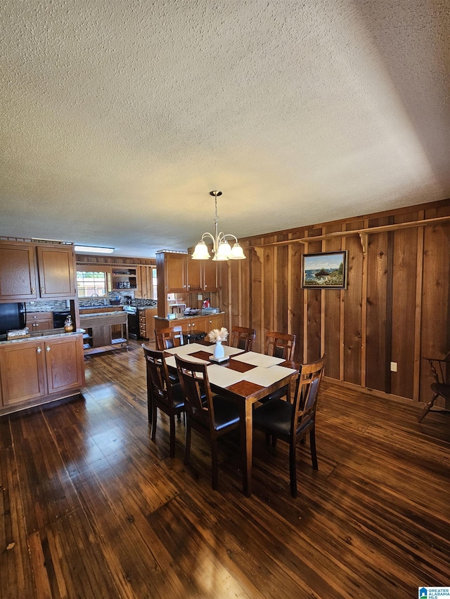 dining space with dark hardwood / wood-style floors, an inviting chandelier, and wood walls