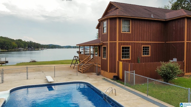 view of swimming pool featuring a patio area, a diving board, and a water view