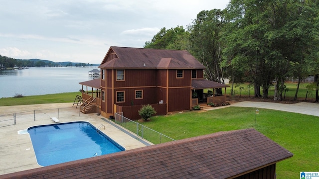 view of swimming pool featuring a diving board, a yard, a water view, and a patio