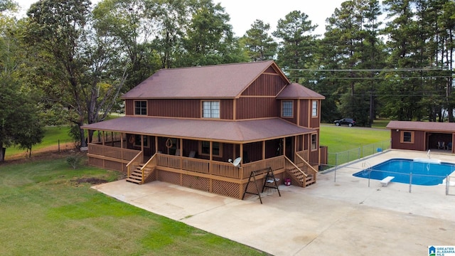 rear view of property featuring a yard, a swimming pool side deck, an outbuilding, and a patio