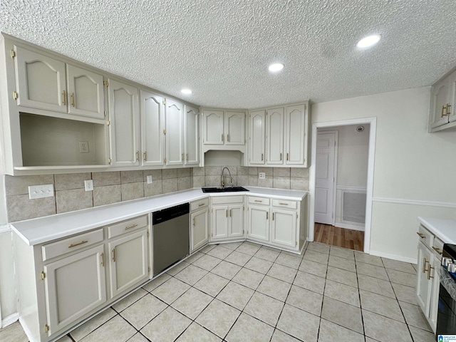 kitchen with sink, stainless steel dishwasher, backsplash, a textured ceiling, and light tile patterned floors