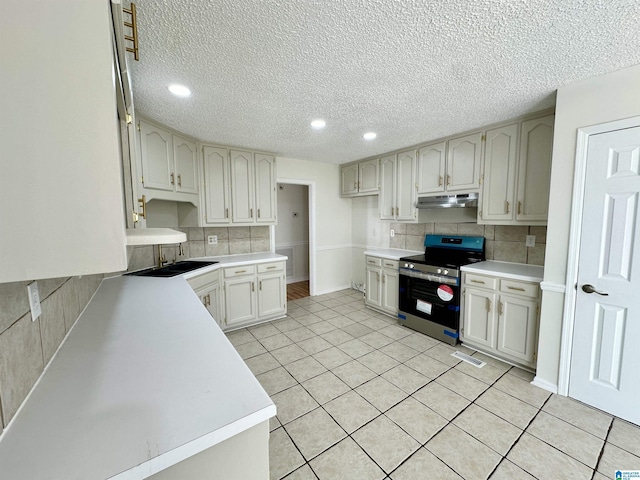 kitchen with electric range, sink, white cabinetry, tasteful backsplash, and light tile patterned flooring