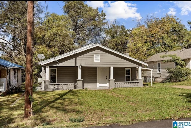 bungalow featuring covered porch and a front yard