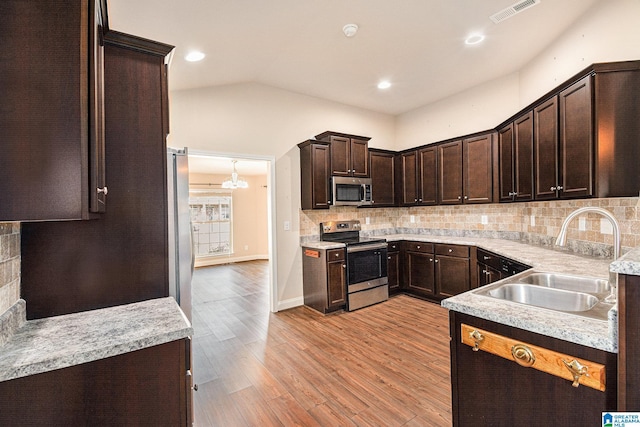 kitchen with appliances with stainless steel finishes, sink, backsplash, dark brown cabinetry, and light hardwood / wood-style floors