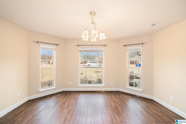 spare room with dark hardwood / wood-style floors and a notable chandelier