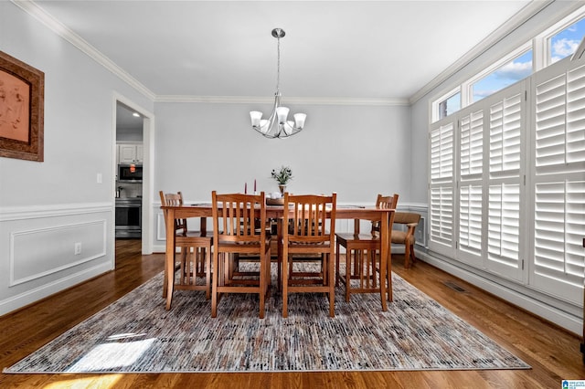 dining room featuring dark hardwood / wood-style floors, ornamental molding, and a chandelier