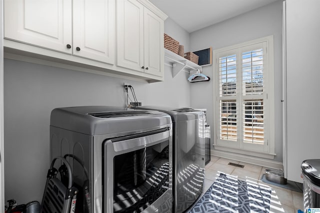 washroom featuring washer and clothes dryer, light tile patterned flooring, and cabinets