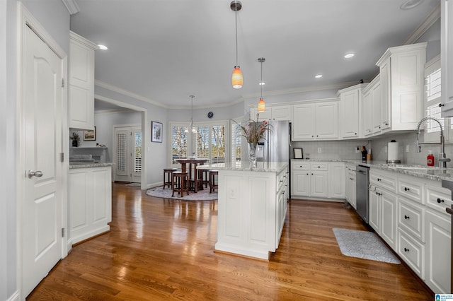 kitchen with dishwasher, white cabinets, decorative backsplash, decorative light fixtures, and a kitchen island