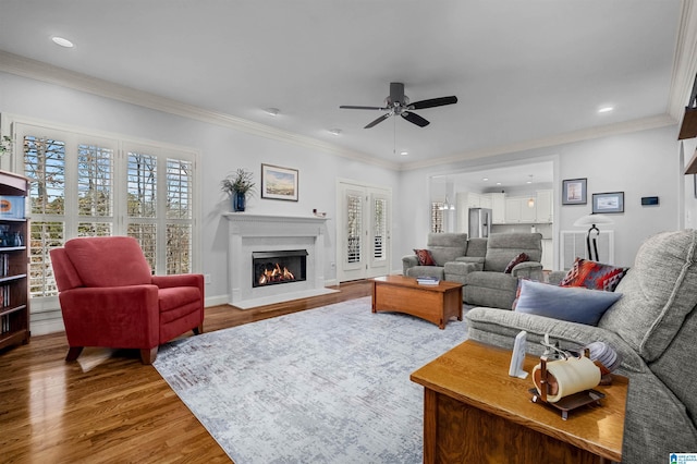 living room featuring ceiling fan, wood-type flooring, and ornamental molding