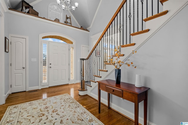 entrance foyer featuring high vaulted ceiling, wood-type flooring, and a notable chandelier