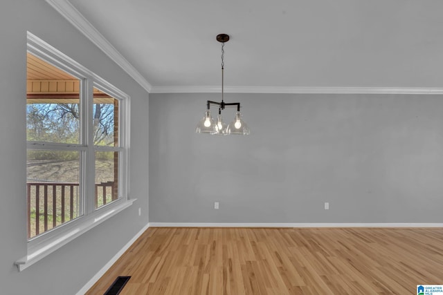 unfurnished dining area featuring light hardwood / wood-style floors, ornamental molding, and a chandelier