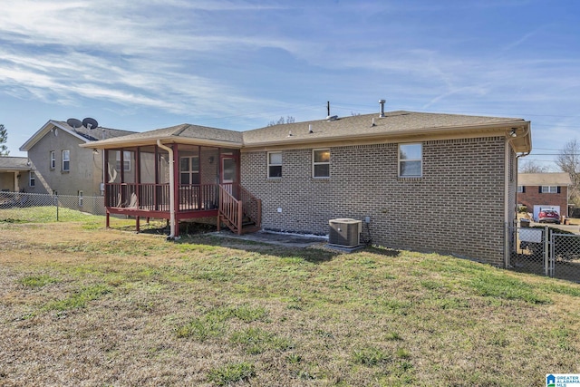 back of property with a sunroom, cooling unit, and a lawn