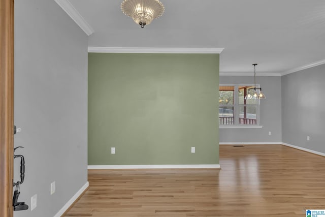 unfurnished room featuring light hardwood / wood-style floors, crown molding, and a notable chandelier