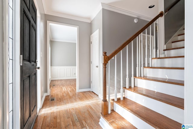 foyer featuring light wood-type flooring and crown molding