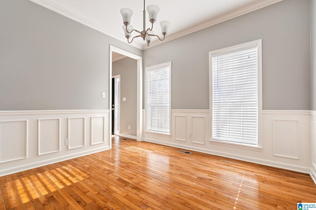 empty room featuring light wood-type flooring, an inviting chandelier, and crown molding