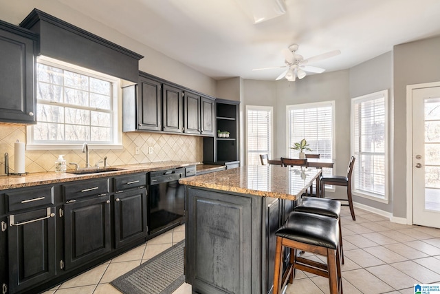 kitchen featuring a center island, ceiling fan, sink, black dishwasher, and a breakfast bar area