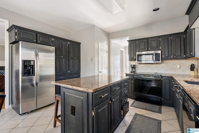 kitchen featuring light tile patterned flooring, backsplash, a kitchen island, and black appliances