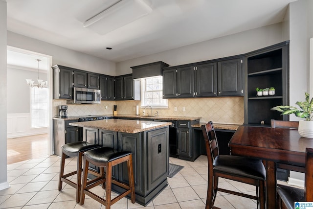 kitchen featuring light stone countertops, light tile patterned floors, pendant lighting, a breakfast bar, and a kitchen island