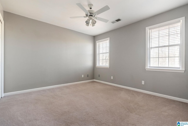 unfurnished room featuring ceiling fan, light colored carpet, and a wealth of natural light