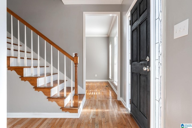 foyer entrance with wood-type flooring, ornamental molding, and a wealth of natural light