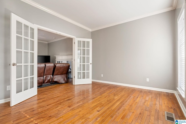 spare room featuring french doors, light hardwood / wood-style flooring, and ornamental molding