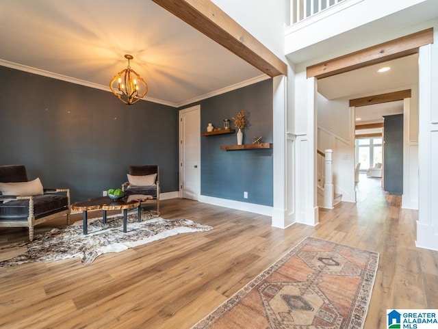 sitting room featuring beam ceiling, light hardwood / wood-style floors, an inviting chandelier, and crown molding