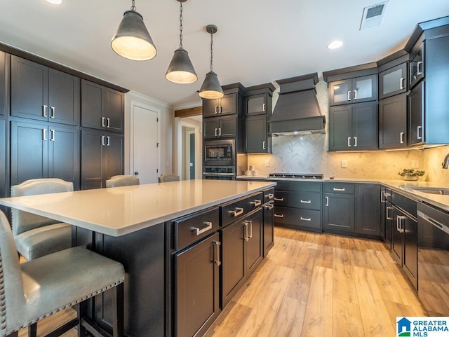 kitchen with pendant lighting, a center island, tasteful backsplash, custom range hood, and stainless steel appliances