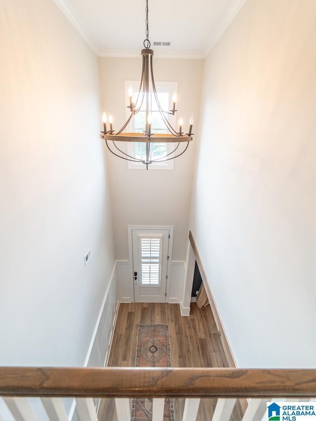 entryway with hardwood / wood-style floors, a notable chandelier, and crown molding