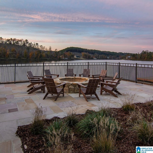 patio terrace at dusk with a water view and a fire pit