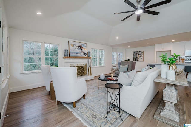 living room with a healthy amount of sunlight, lofted ceiling, and light hardwood / wood-style floors