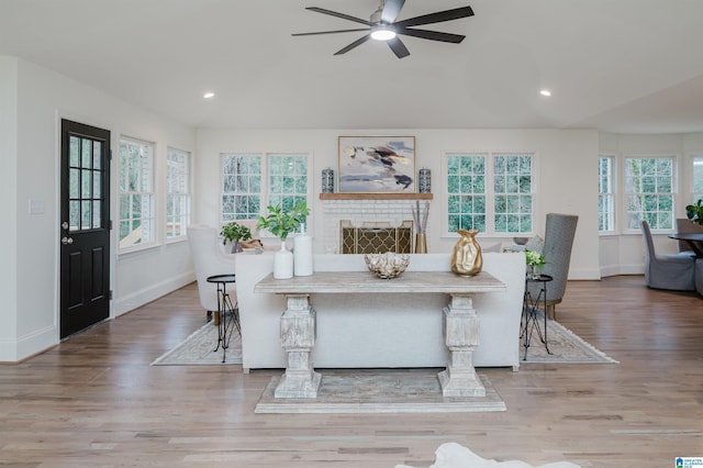 dining space with hardwood / wood-style floors, ceiling fan, and a brick fireplace