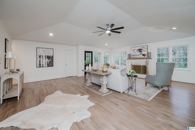 living room with ceiling fan, light hardwood / wood-style floors, and vaulted ceiling