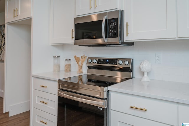 kitchen with light stone countertops, appliances with stainless steel finishes, tasteful backsplash, hardwood / wood-style flooring, and white cabinets