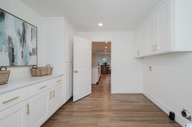 clothes washing area with cabinets, sink, hookup for a washing machine, and light hardwood / wood-style flooring