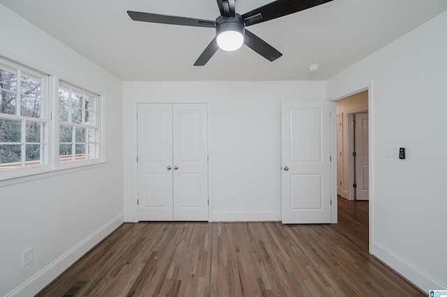 unfurnished bedroom featuring ceiling fan, wood-type flooring, and a closet