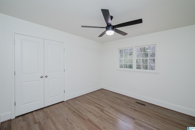 unfurnished bedroom with ceiling fan, a closet, and light wood-type flooring