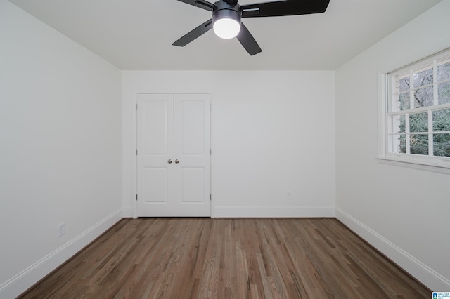 unfurnished bedroom with ceiling fan, a closet, and hardwood / wood-style flooring