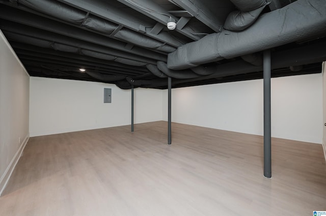 basement with light wood-type flooring and electric panel