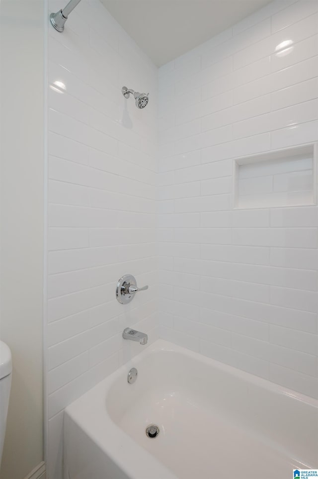 bathroom featuring tiled shower / bath combo and toilet