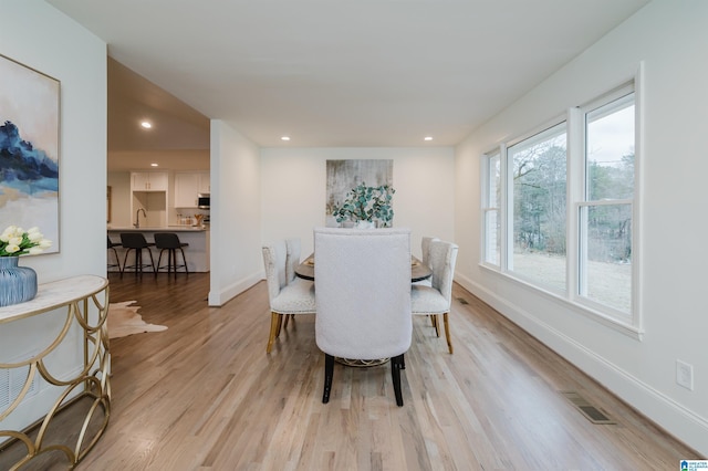 dining space with light hardwood / wood-style flooring, plenty of natural light, and sink