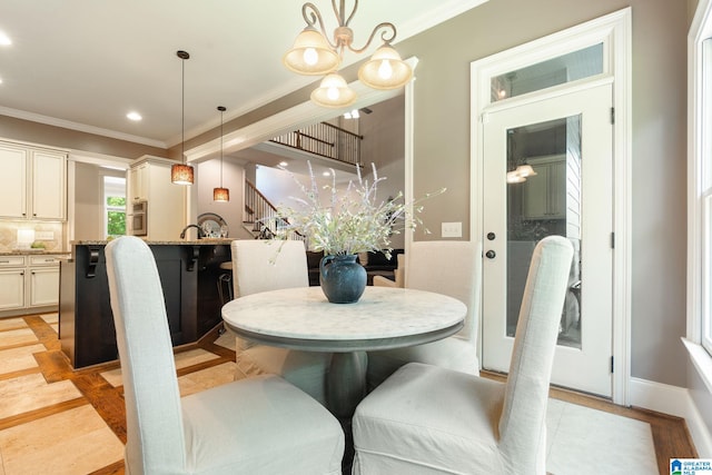 dining space with light wood-type flooring, ornamental molding, and an inviting chandelier