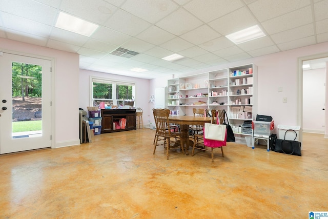 dining space with a drop ceiling and concrete flooring