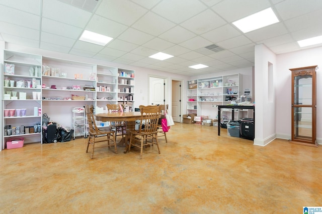 dining space featuring built in shelves, a paneled ceiling, and concrete floors