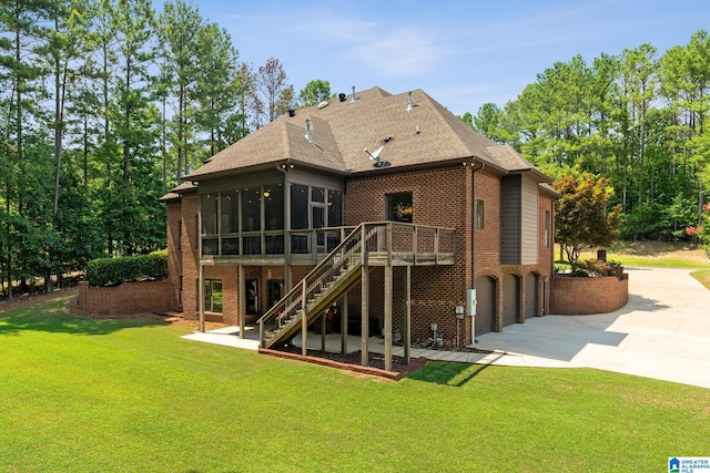 back of property with a lawn, a sunroom, a wooden deck, a garage, and a patio